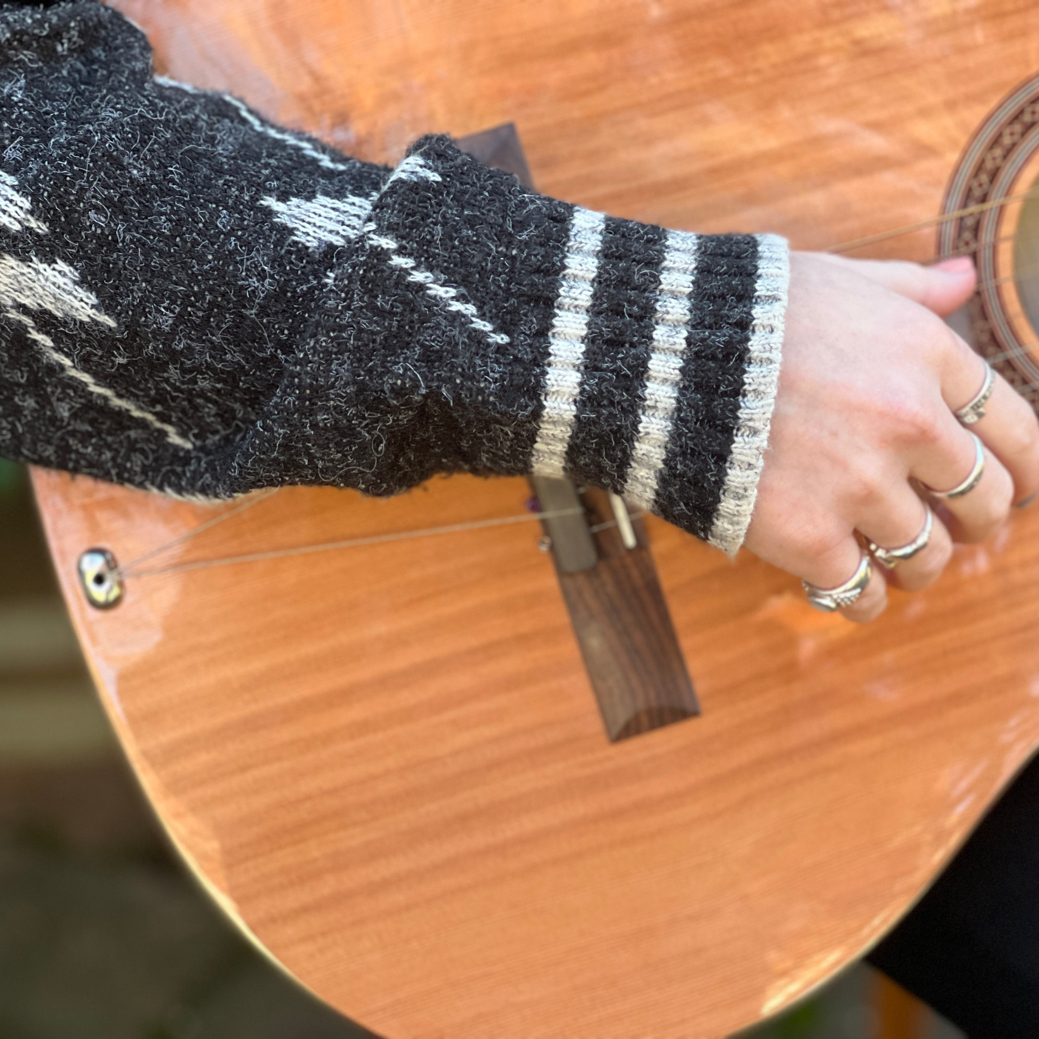 closeup of a person's arm and hand playing an acoustic guitar with TurboStrand